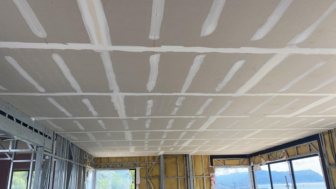 A plasterboard ceiling with all joints and screw heads taped and mudded, seen from below