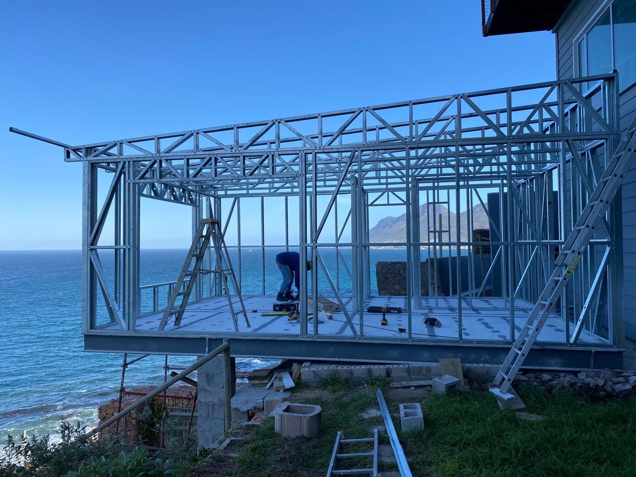 Light steel frame extension cantilevered on steel beams above the ocean