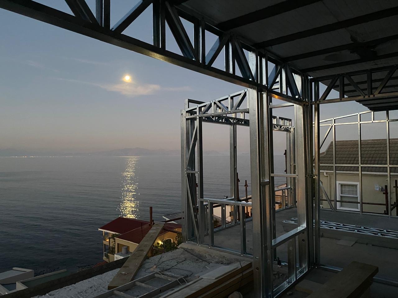 Moon rising over the sea, seen through a light steel frame at dusk