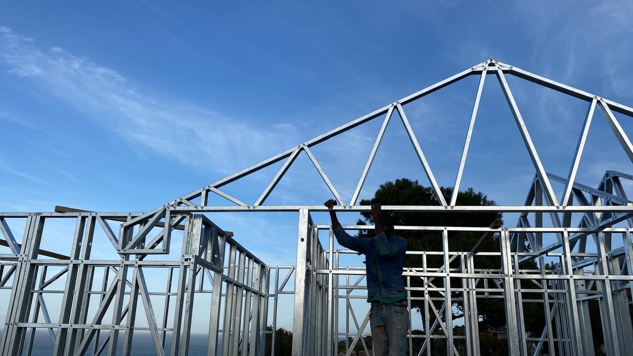 Team member setting a roof truss on a light steel frame