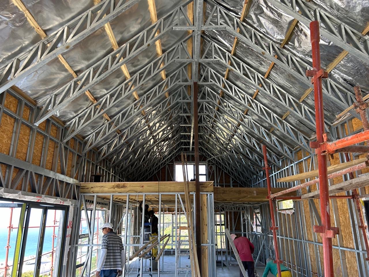 Galvanised steel roof trusses and insulation seen from inside the frame